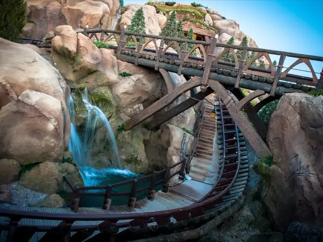 The mine track of Seven Dwarfs Mine Train diving past a waterfall at Magic Kingdom