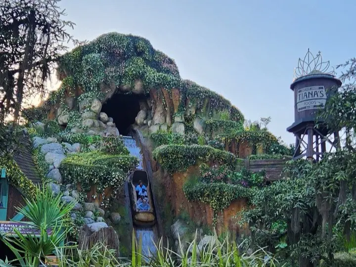 A log boat dropping down the mossy face of Tiana's Bayou Adventure at Magic Kingdom