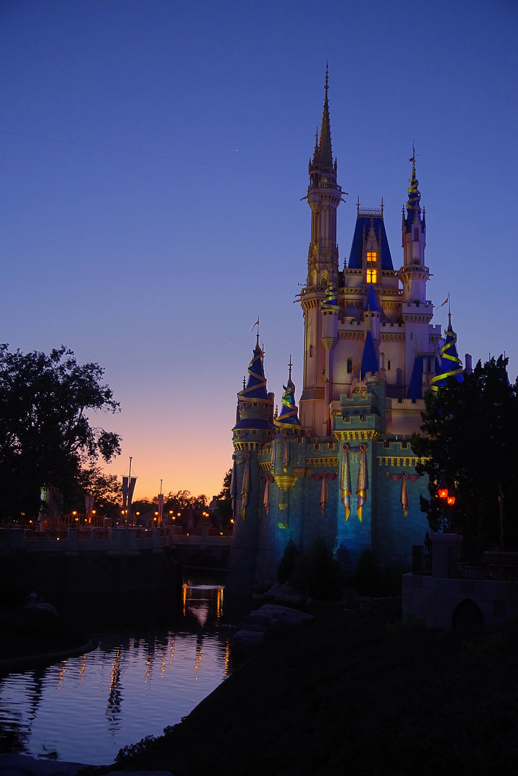Cinderella Castle illuminated above the water at dusk